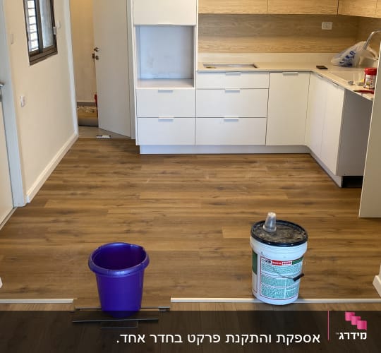 פרקט עץ מותקן על רצפת מטבח עם דלי וכלים